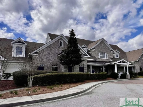 Exterior view of 106 Danbury Court, a 3-bedroom, 2.5-bathroom end-unit townhome with a screened-in porch overlooking wooded views in the gated community of Savannah Quarters, Pooler, GA.